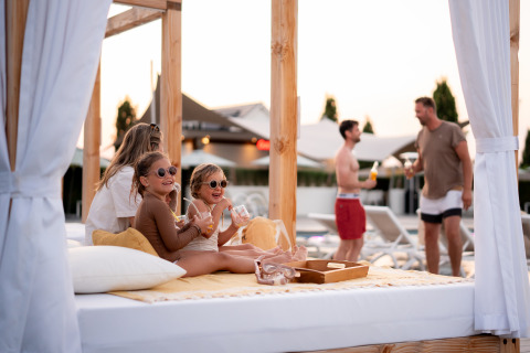Kinderen en volwassenen ontspannen op een buitenbed bij Berg Lodge - Sauna, Resort Mooi Bemelen, Nederland.