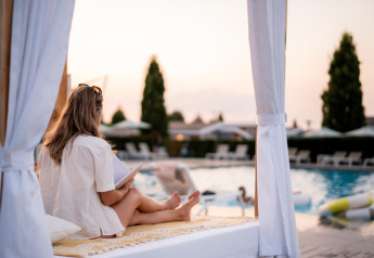 Vrouw leest ontspannen bij het zwembad bij Biebosch, Resort Mooi Bemelen, Nederland tijdens zonsondergang.