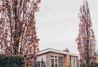 La cabaña Biebosch en Resort Mooi Bemelen, Países Bajos, rodeada de árboles altos y caminos húmedos.