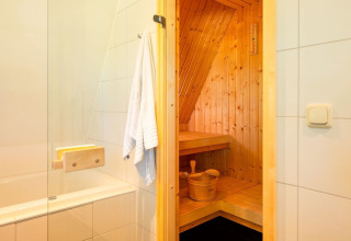 Moderne badkamer met witte tegels en een houten sauna bij Hof van Salland, Overijssel, Nederland.