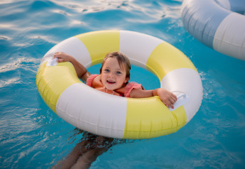 Un bambino sorride in un salvagente giallo e bianco nella piscina del Biebosch Lodge, Resort Mooi Bemelen, Paesi Bassi.