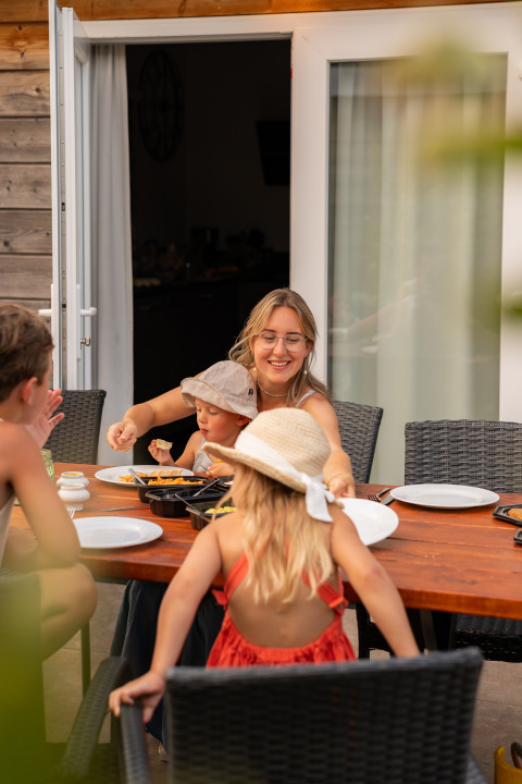Gezin geniet van een maaltijd buiten bij Lodge Biebosch, Resort Mooi Bemelen, Nederland, op een zomerse dag.