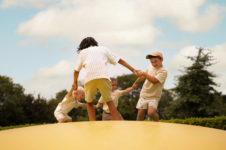 Children playing together outside on a bouncy platform at Lodge Biebosch, Resort Mooi Bemelen, Netherlands.