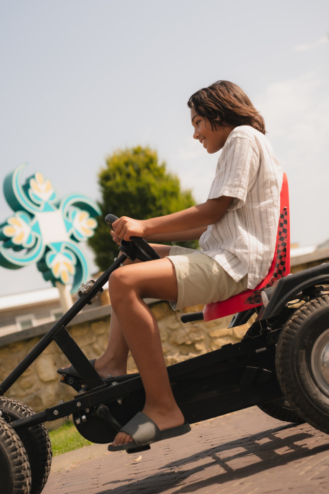 Joven montando un kart en la cabaña Biebosch del Resort Mooi Bemelen, Países Bajos, en un día soleado.