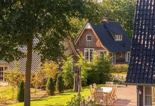 Zonnige tuin met houten tuinset en moderne vakantiehuizen in Hof van Salland, Overijssel, Nederland.