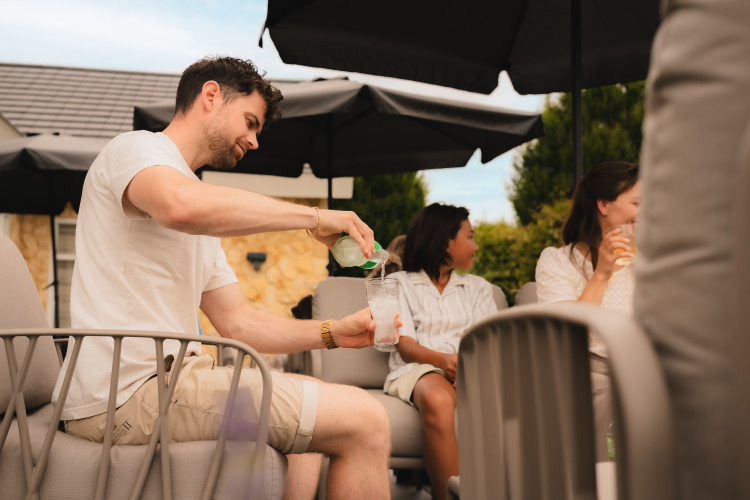 Un hombre sirve una bebida en la terraza de Biebosch - Sunshower, Resort Mooi Bemelen, Países Bajos.