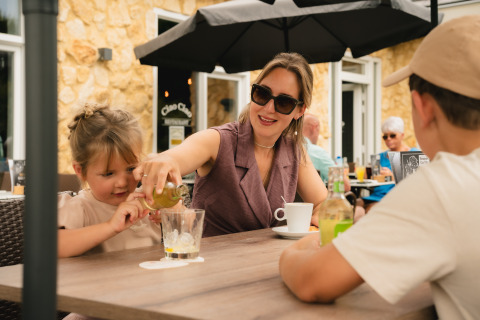 Madre e figli si godono una bevanda a un tavolo all'aperto presso Biebosch - Sunshower, Resort Mooi Bemelen.