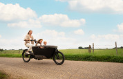 En glad familie cykler på en landevej nær Biebosch - Sunshower, Resort Mooi Bemelen, Holland, om sommeren.