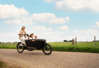 En glad familie cykler på en landevej nær Biebosch - Sunshower, Resort Mooi Bemelen, Holland, om sommeren.