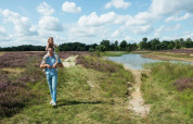 Father carrying daughter on shoulders on a trail by a pond at Camping GT Keiheuvel, Antwerp, Belgium.
