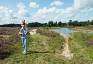 Padre con figlia sulle spalle cammina vicino a un laghetto al Camping GT Keiheuvel, Anversa, Belgio.