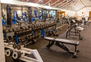 Gym with dumbbells, benches, and fitness machines at Camping GT Keiheuvel holiday park in Antwerp, Belgium.