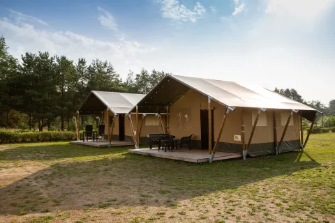 Dos tiendas safari con terraza en Camping GT Keiheuvel en Bélgica, rodeadas de naturaleza y cielo despejado.