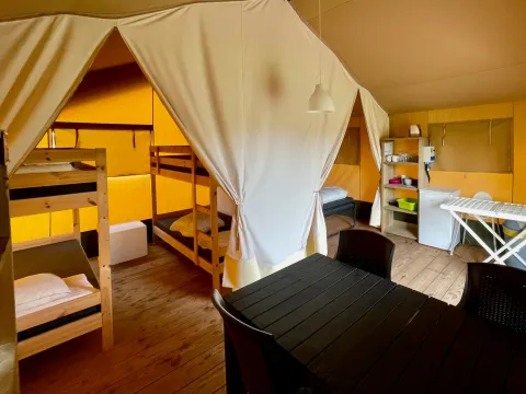 Inside a safari tent at Camping GT Keiheuvel in Belgium, featuring bunk beds, dining table, and kitchenette.