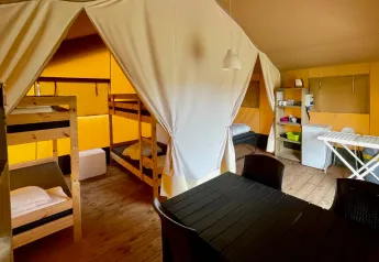 Inde i en safaritelte på Camping GT Keiheuvel i Belgien, med køjesenge, bord og et lille køkkenhjørne.