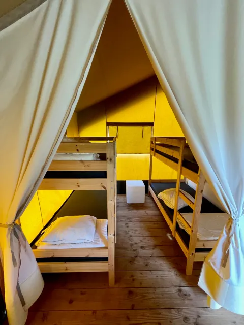 Intérieur d'une tente safari au Camping GT Keiheuvel en Belgique, avec lits superposés et sol en bois.