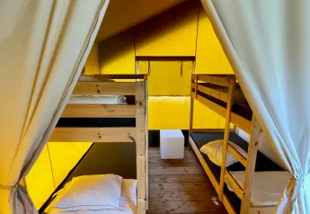 Interno della tenda safari al Camping GT Keiheuvel in Belgio con letti a castello e pavimento in legno.