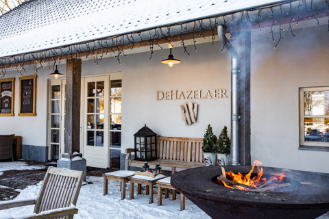 Buitenaanzicht van De Hazelaer restaurant bij Hof van Salland, met vuurkorf en sneeuw in Overijssel.