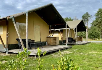 Tende safari presso Camping GT Keiheuvel in Belgio, con veranda in legno rialzata e area relax all’aperto.