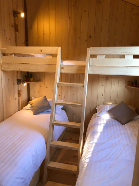Gemütliches Zimmer mit vier Schlafplätzen in Etagenbett-Design, komplett aus hellem Holz gestaltet.