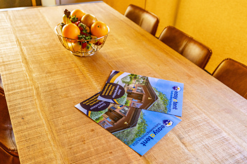 Houten tafel met easyTent folders en een fruithouder in Bijela Uvala Safaritent Lodge, Camping Bijela Uvala, Kroatië.