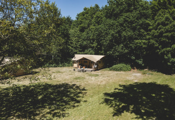 Tienda safari Glamping tent La Vida en Resort de Parel, Países Bajos, entre árboles y naturaleza verde.