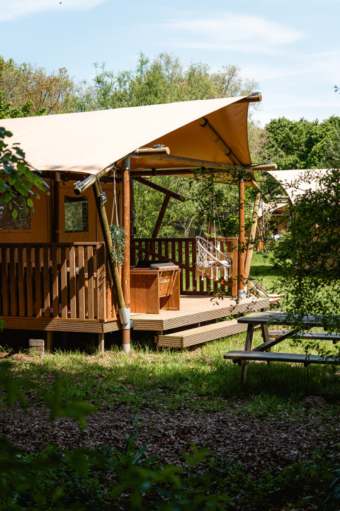 Tente safari glamping La Vida au Resort de Parel aux Pays-Bas, terrasse en bois et végétation autour.