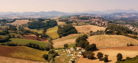 Aerial view of Camping Suasa holiday park in Marche, Italy, surrounded by fields and rolling hills.