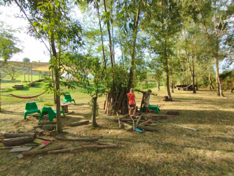 Bambini che giocano all'aperto tra alberi e tronchi al Camping Suasa nelle Marche, Italia, immersi nella natura.