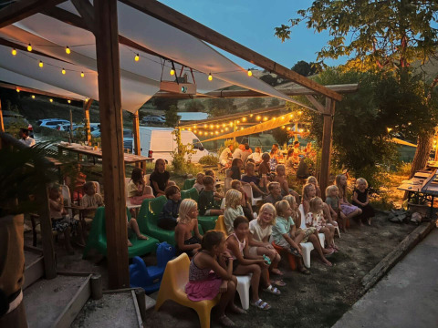 Children and adults enjoy a lovely evening event under lights at Camping Suasa holiday park in Marche, Italy.