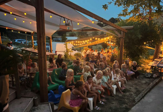 Bambini e adulti trascorrono una serata piacevole sotto le luci a Camping Suasa, nelle Marche, Italia.