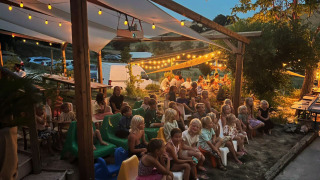 Children and adults enjoy a lovely evening event under lights at Camping Suasa holiday park in Marche, Italy.
