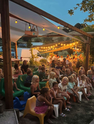 Kinderen en volwassenen genieten van een gezellige avond bij Camping Suasa vakantiepark in Marche, Italië.