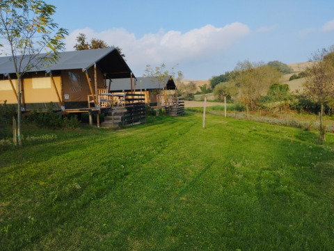 Camping Suasa nelle Marche, Italia, con tende lodge su terrazze in legno immerse nel verde della campagna.