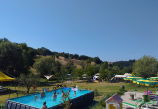 Camping Suasa holiday park in Marche, Italy, featuring a pool with kids swimming and tents in the background.