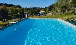 Buitenzwembad op Camping Suasa vakantiepark in Marche, Italië, omgeven door natuur en tenten.
