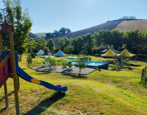 Camping Suasa holiday park in Marche, Italy, featuring a playground, tents, swimming pool and hill views.