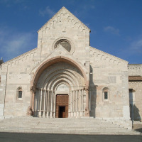 Facade of a large Romanesque church near Castelleone di Suasa, Marche, Italy, with a clear blue sky.