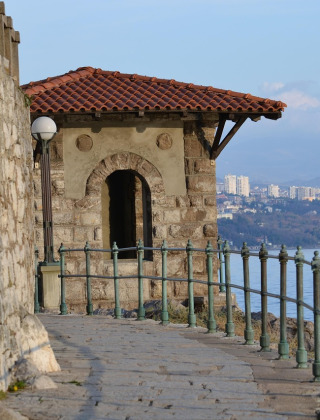 Paseo de piedra junto a la costa cerca de Labin, Istria, Croacia, con vista al mar y ciudad al fondo.