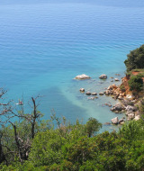 Vista costera cerca de Labin, Istria, Croacia, con rocas, vegetación y agua de mar azul cristalina.