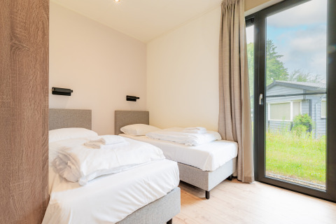 Lichte tweepersoons slaapkamer in Vakantievilla Amalia 6 met groot raam bij Hofparken De Bergvennen.