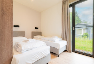 Lichte tweepersoons slaapkamer in Vakantievilla Amalia 6 met groot raam bij Hofparken De Bergvennen.