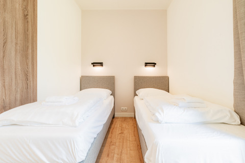 Moderne slaapkamer met twee eenpersoonsbedden in Vakantievilla Amalia 6 met hottub bij Hofparken De Bergvennen.