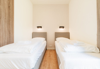 Dormitorio moderno con dos camas individuales en Vakantievilla Amalia 6 con bañera de hidromasaje en Hofparken De Bergvennen.