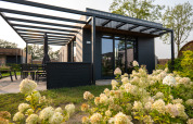 Moderne Ferienvilla mit Terrasse, Gartenmöbeln und Blumen bei Hofparken De Bergvennen in den Niederlanden.