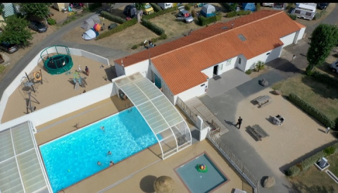 Vue aérienne du Flower Camping Le Pré des Sables avec piscine, aire de jeux et bâtiments en France.
