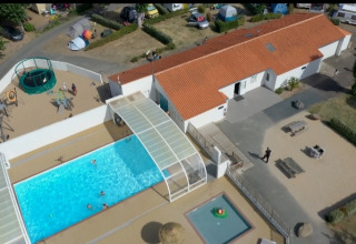 Aerial view of Flower Camping Le Pré des Sables with pool, playground, and campsite buildings in France.