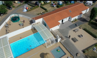 Aerial view of Flower Camping Le Pré des Sables with pool, playground, and campsite buildings in France.