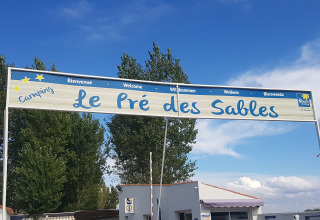 Panneau d'entrée du Flower Camping Le Pré des Sables en Pays de la Loire, France, sous un ciel bleu.