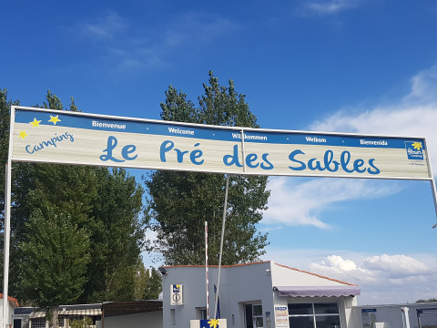 Insegna d'ingresso di Flower Camping Le Pré des Sables nel Pays de la Loire, Francia, con cielo blu limpido.